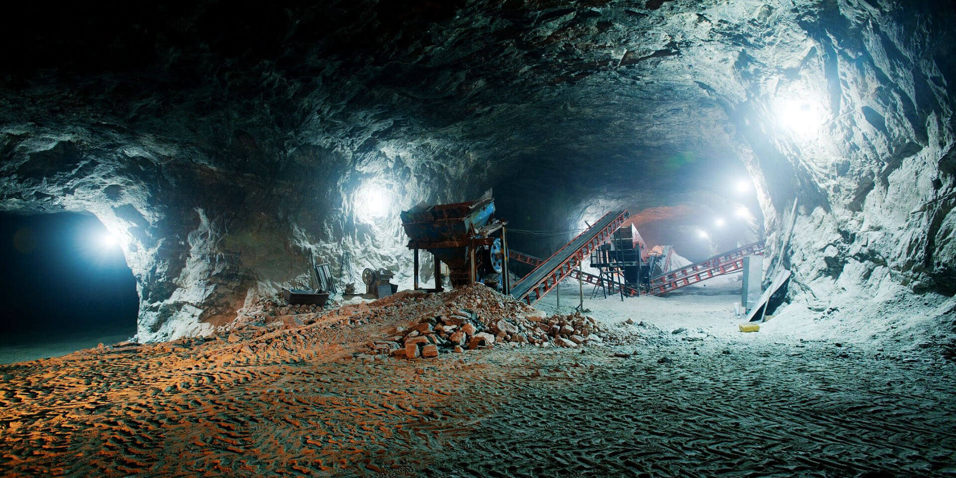 Dark dirty abandoned uranium mine with rusty remnants of railway.